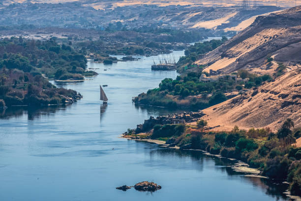 puesta de sol sobre el río nilo en la ciudad de asuán con costas arenosas y desérticas - felucca boat fotografías e imágenes de stock