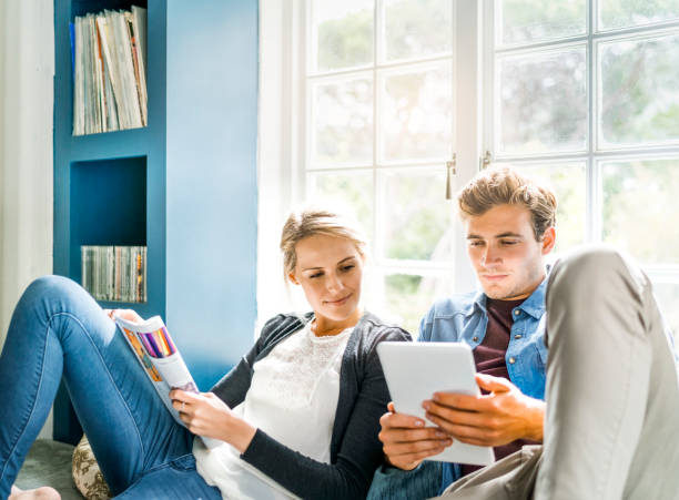 Couple looking at digital tablet against window