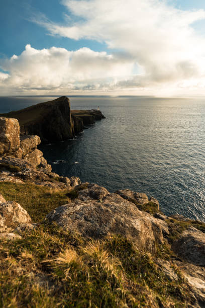 istock Sunset at Neist Point Lighthouse with rocky shore, dramatic sky and sun bursting through clouds before sunset (Isle of Skye, Scotland, Europe) 1126882264