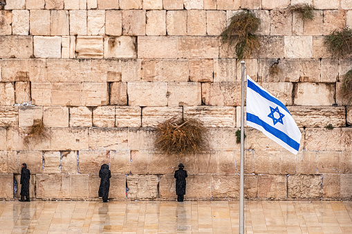 Israeli flag against the western wall  on a cloudy day