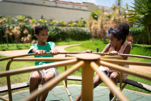 hermanos jugando en la glorieta - carousel merry go round child african descent fotografías e imágenes de stock