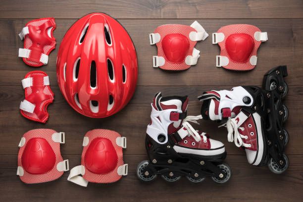 roller skates and protection roller skates and body parts protection on brown table. top view of inline rollers, helmet, knee pads, wrist guards and elbow pads over wooden background elbow pad stock pictures, royalty-free photos & images