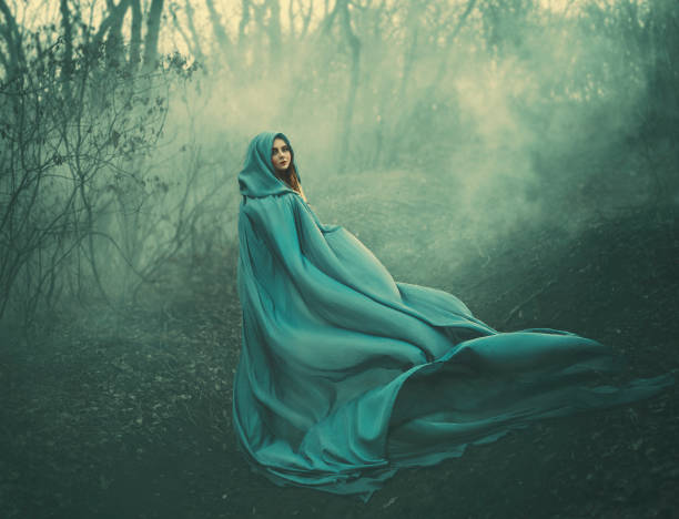 istock attractive large lady in long blue summer light waving raincoat runs through forest with bare trees and mysterious white smoke and magical fog, charming sorceress escapes from a fairytale monster 1126891737