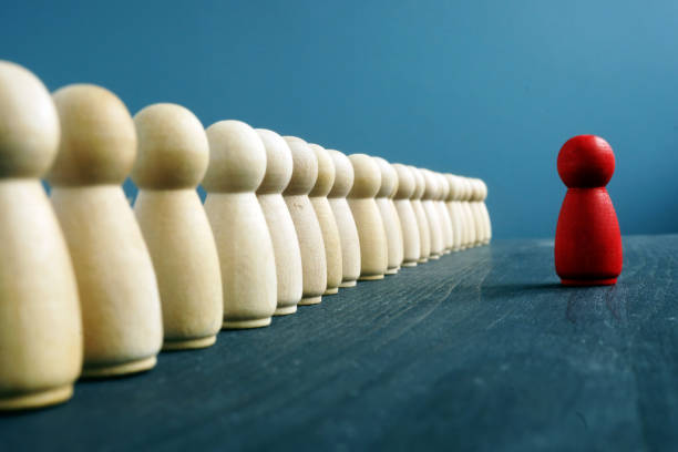 istock Leadership training. Line of figurines and red one opposite. 1126892308