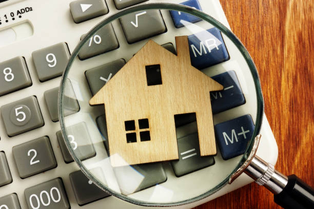 istock House value. Model of home, calculator and magnifying glass. 1126892613
