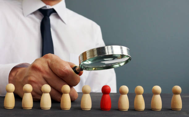 istock Recruiter looking through magnifying glass on candidates. Hiring and recruiting. 1126892671