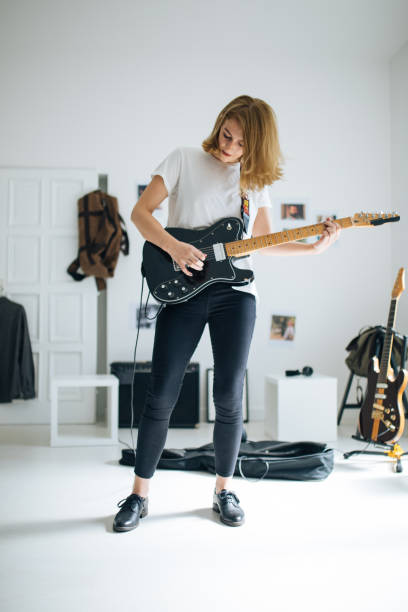 istock Young woman playing electric guitar 1126897336