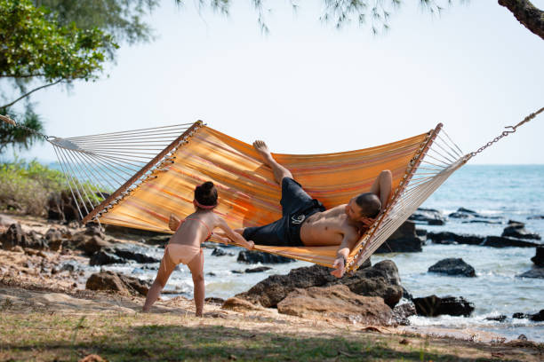 Father and daughter playing on the beach hammock