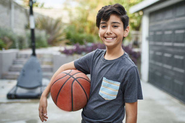 庭でバスケット ボールに立って微笑む少年の肖像画 - 10歳から11歳 ストックフォトと画像