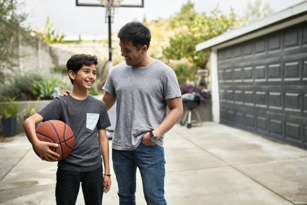 padre hablando al hijo con baloncesto en yarda - pre teen boy fotografías e imágenes de stock