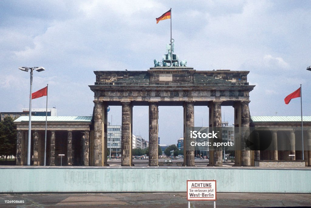 Historic image from July 1980: A look from West Berlin over the Berlin wall to Brandenburg Gate and East Berlin. Sign with "Caution: You are leaving West Berlin" in the foreground. Scanned Slide. Berlin Wall Stock Photo