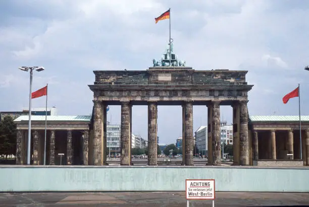 Historic image from July 1980: A look from West Berlin over the Berlin wall to Brandenburg Gate and East Berlin. Sign with "Caution: You are leaving West Berlin" in the foreground. Scanned Slide.