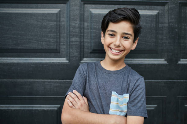 istock Smiling boy with arms crossed against wall at yard 1126908816