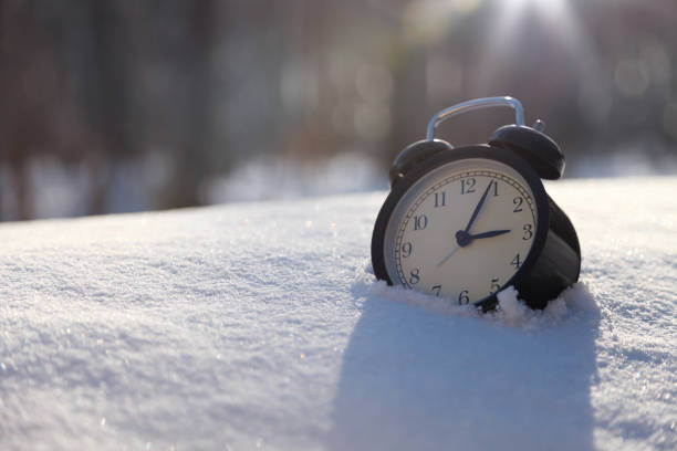 Closeup image of alarm clock in snow. Spring time concept image with copyspace