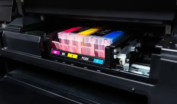 Photo of Close-up shot of a CMYK ink cartridges in a color printer.
