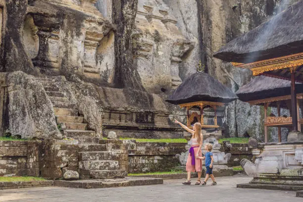 Mom and son on background of Gunung Kawi. Ancient carved in the stone temple with royal tombs. Bali, Indonesia. Traveling with children concept..