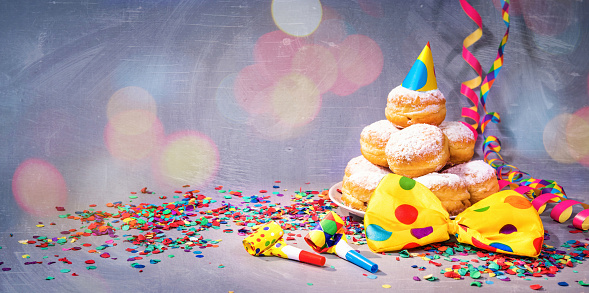 Krapfen, berliner or donuts with bow tie, streamers and confetti. Colorful carnival or birthday background