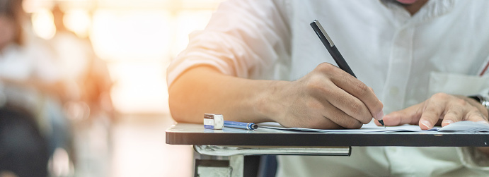 School exam student's taking educational admission test in class, thinking hard, writing answer in university classroom, education and world literacy day concept