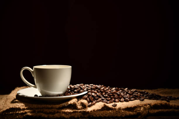 Cup of coffee and coffee beans on black background