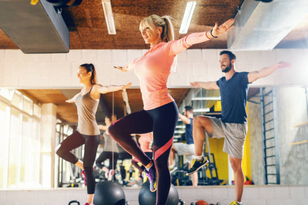 istock Trainer showing to the group balance exercise in gym. In background their mirror reflection. 1126920500
