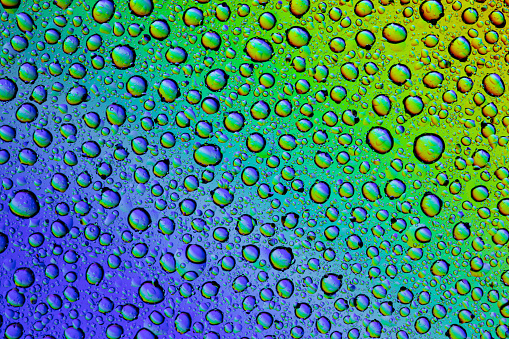 Drops of water on the glass, with the reflection of the rainbow. Background