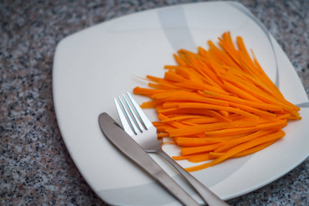 A plate of carrots with silver spoon and fork stock photo