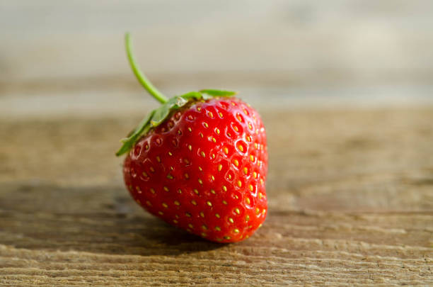 istock one strawberry on a wooden table 1126922900