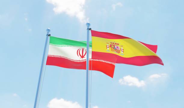 istock Spain and Iran, two flags waving against blue sky 1126924180