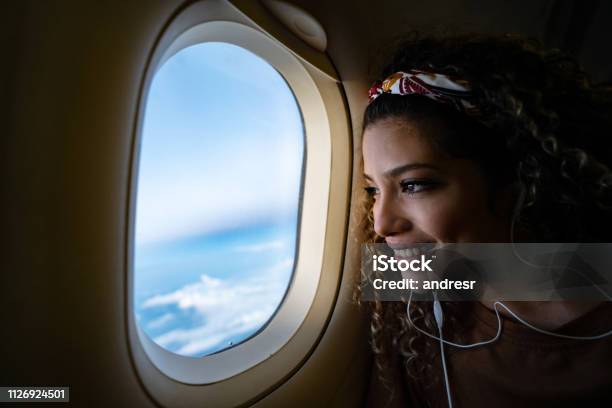 Woman Traveling By Airplane And Listening To Music Stock Photo - Download Image Now - Airplane, Window, Travel