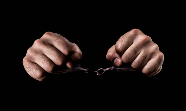 Human hands in handcuffs and torn chains stock photo