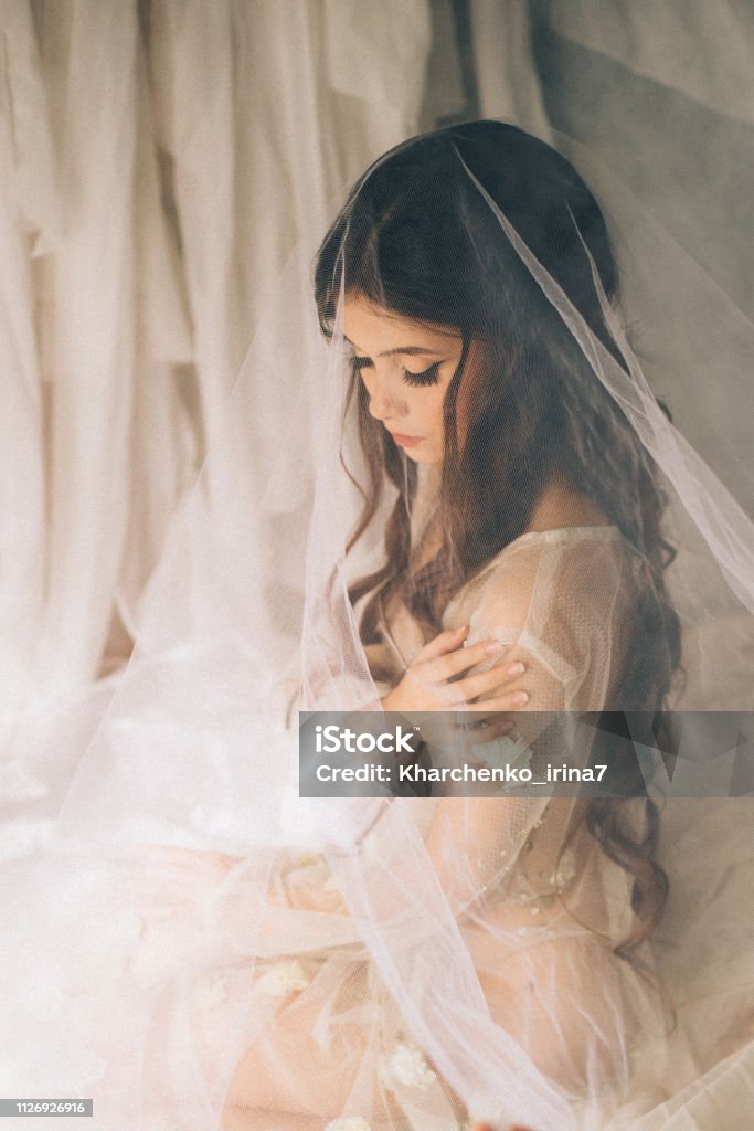 Pretty Attractive Tender Innocent Girl With Big Doll Eyes Dressed In A White Transparent Dress Dark Curled Hair Covered With A Light Elegant Veil Happy Morning Of The Young Beloved Bride Stock Pretty Attractive Tender Innocent Girl With Big Doll Eyes Dressed In A White Transparent Dress Dark Curled Hair Covered With A Light Elegant Veil Happy Morning Of The Young Beloved Bride Stock