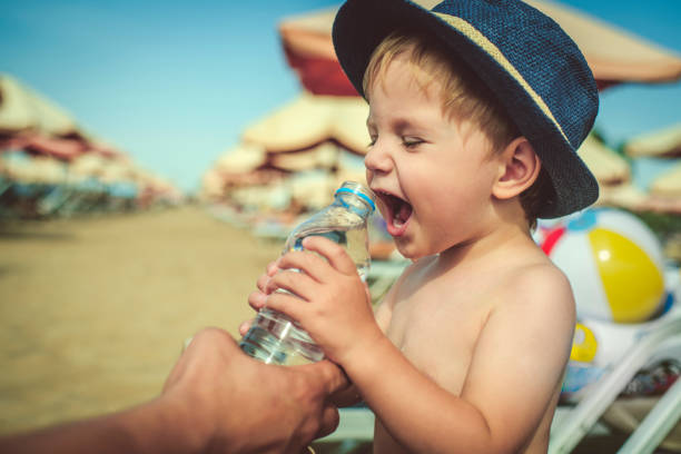 istock Father helping his son to drink water on the beach 1126928129
