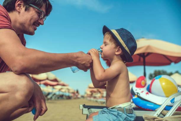 istock Father helping his son to drink water on the beach 1126928153