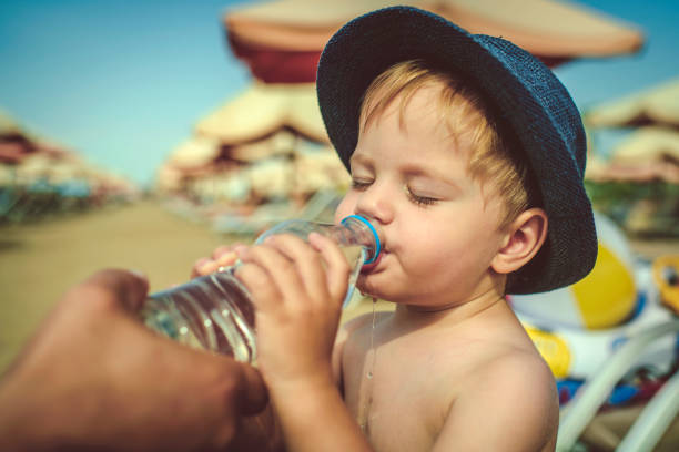 istock Father helping his son to drink water on the beach 1126928159