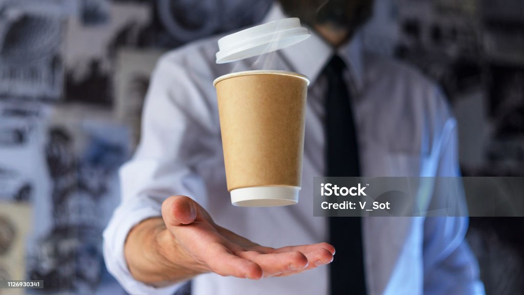 Barista and levitating paper cup of hot coffee Levitating in the air paper cup with hot coffee. Barista, a bearded young man in a white shirt with a tie, creates miracles - advertises his drink, causing it to soar. Logoplacement concept Adventure Stock Photo