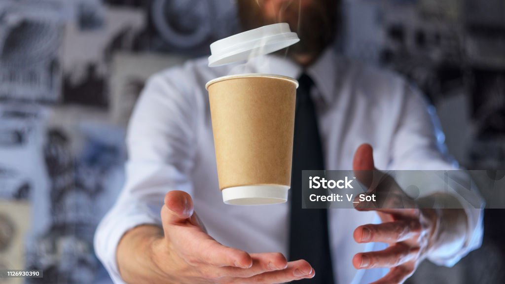 Barista and levitating paper cup of hot coffee Barista, a bearded young man in a white shirt with a tie trying to catch a paper cup with hot coffee. Background for advertising. Empty place to your logo placement Adventure Stock Photo