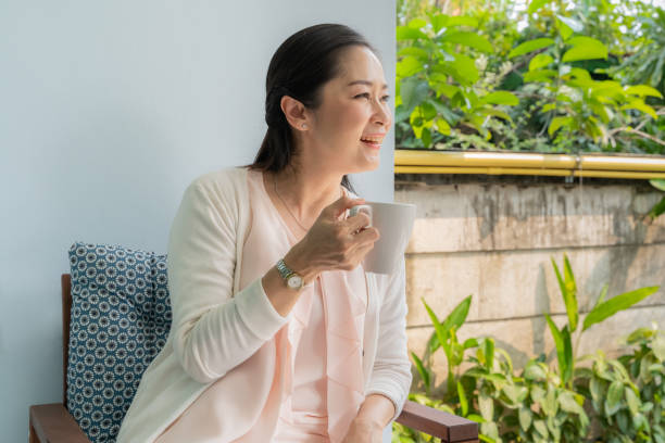 istock Middle-aged Asian women sit and sip coffee in the backyard. 1126931130