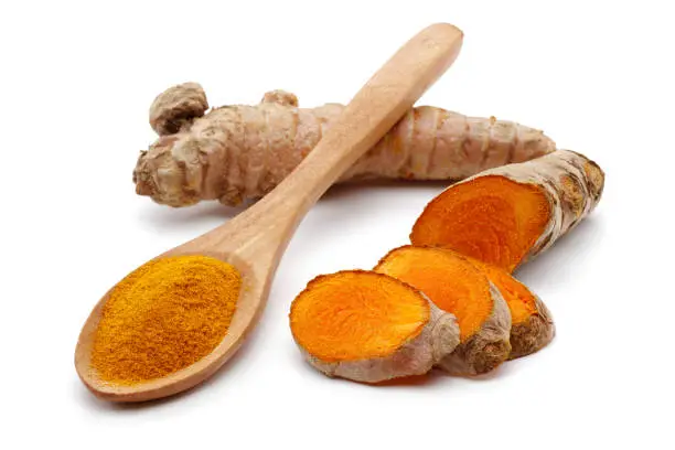 Photo of Fresh turmeric with slices and curcuma in wooden spoon