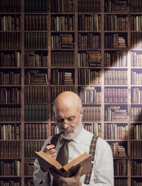 istock Academic professor in the library holding a book 1126933732