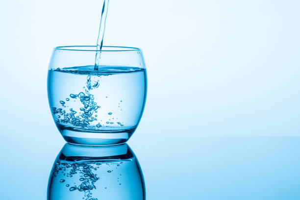 Flowing pure water into glass on blue