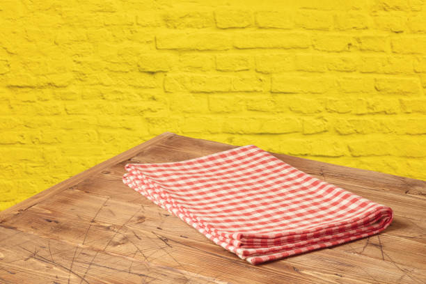 istock Empty wooden table with tablecloth over yellow brick stone wall background. 1126936448