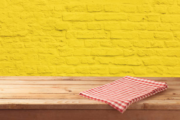istock Empty wooden table with tablecloth over yellow brick stone wall background. 1126936457