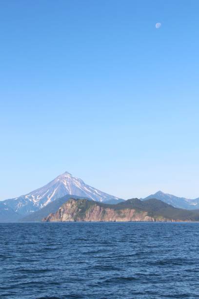 istock View of Vilyuchinsky volcano (also called Vilyuchik) from water. Moon is visible in the sky. 1126937009