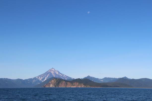 istock View of Vilyuchinsky volcano (also called Vilyuchik) from water. Moon is visible in the sky. 1126937011