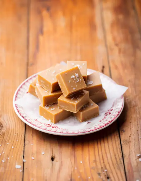 Fresh caramel fudge candies on a plate. Wooden background. Copy space