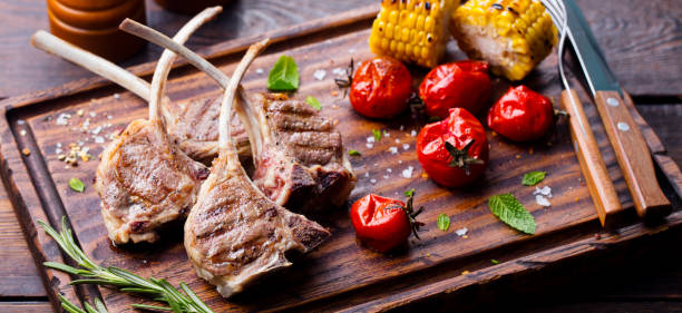 costillas de cordero a la parrilla sobre tabla de cortar con verduras asadas. fondo de madera. - rack of lamb chop cutlet rosemary fotografías e imágenes de stock