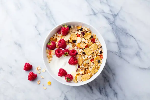 Healthy breakfast. Fresh granola, muesli with yogurt and berries on marble background. Top view