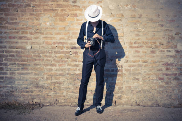 Unrecognizable photographer taking picture with medium format camera. Unrecognizable fedora man photographing with vintage medium format photo camera. 1930s style men image created 1920s old fashioned stock pictures, royalty-free photos & images