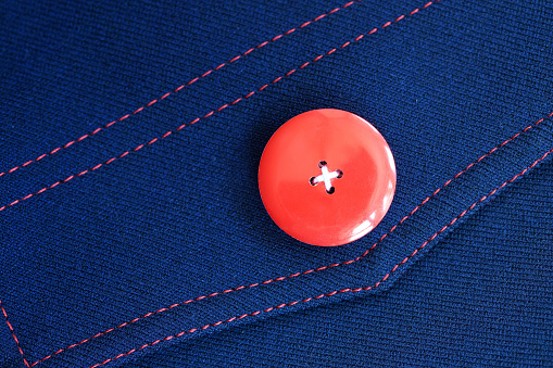 Red button on blue textile background