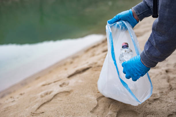 istock Young Man Picking Up Plastic Bottles From Riverbank 1126947004